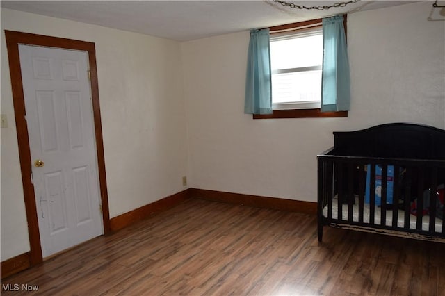 bedroom featuring dark hardwood / wood-style floors and a nursery area