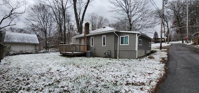 view of snow covered exterior with central AC unit and a deck