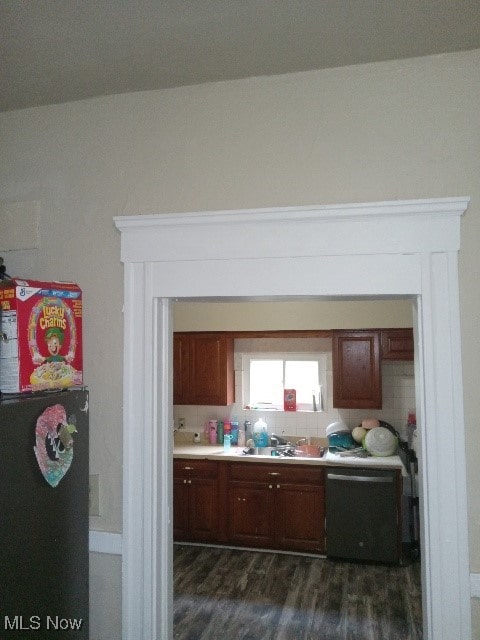 kitchen with vaulted ceiling, sink, black dishwasher, and dark wood-type flooring