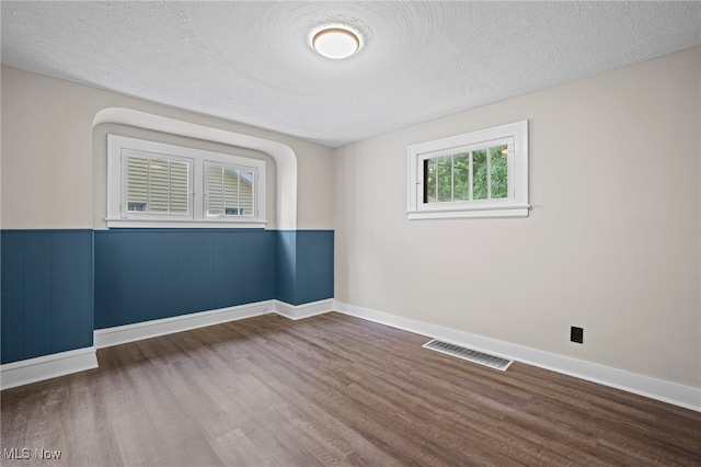 empty room featuring wood-type flooring and a textured ceiling