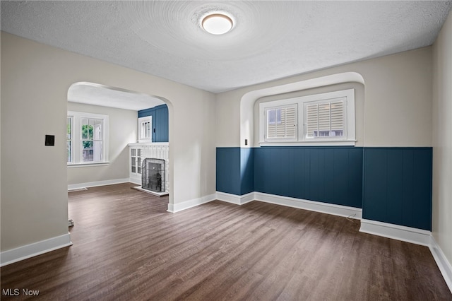 empty room with a textured ceiling and dark hardwood / wood-style flooring