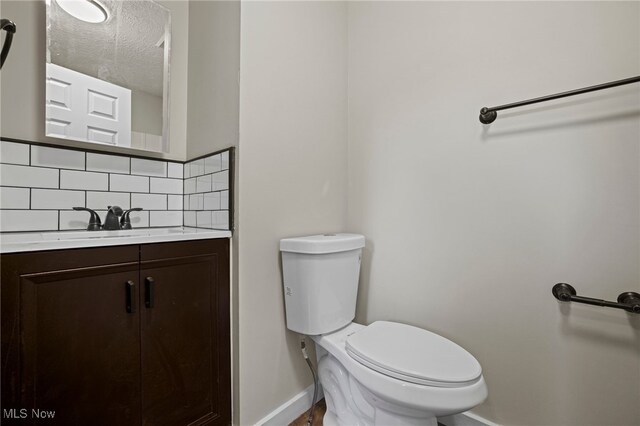 bathroom with tasteful backsplash, vanity, a textured ceiling, and toilet