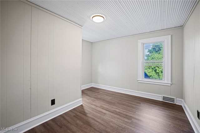 unfurnished room with wooden walls and dark wood-type flooring