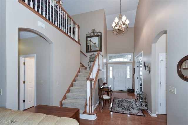 foyer entrance with wood-type flooring, a high ceiling, and an inviting chandelier