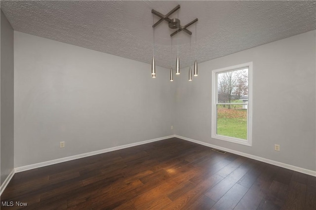 empty room with a textured ceiling and dark wood-type flooring