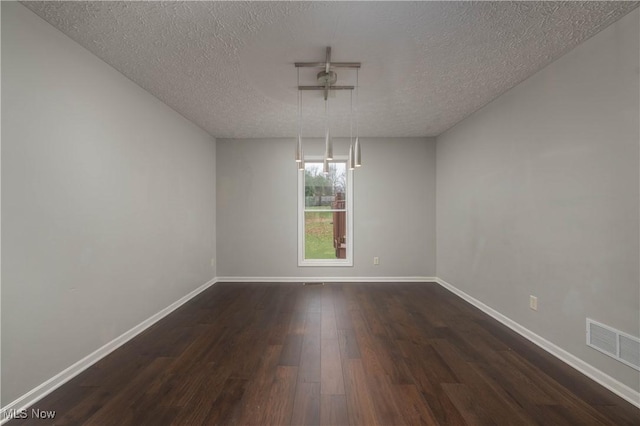 empty room with dark hardwood / wood-style flooring and a textured ceiling