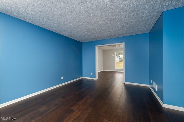 spare room with a textured ceiling and dark wood-type flooring