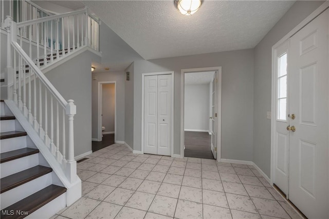 entrance foyer with a textured ceiling and light tile patterned flooring