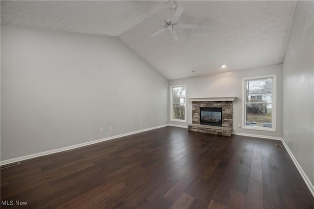 unfurnished living room with vaulted ceiling, dark hardwood / wood-style floors, ceiling fan, a fireplace, and a textured ceiling