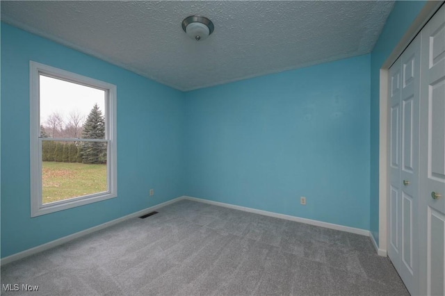 unfurnished bedroom featuring a closet, carpet floors, and a textured ceiling