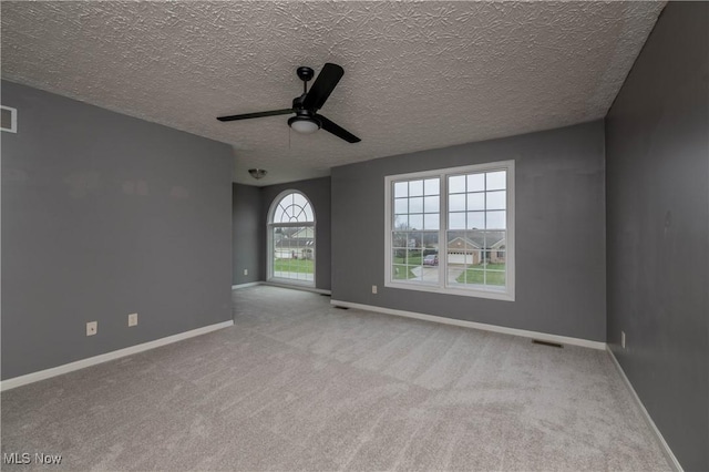 spare room featuring ceiling fan, light colored carpet, and a textured ceiling