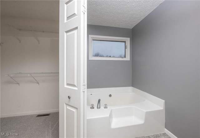 bathroom with a textured ceiling and a tub