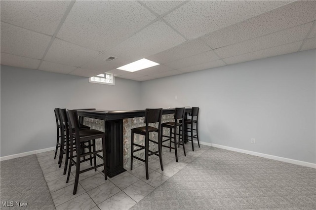 dining space with carpet flooring, bar, and a drop ceiling