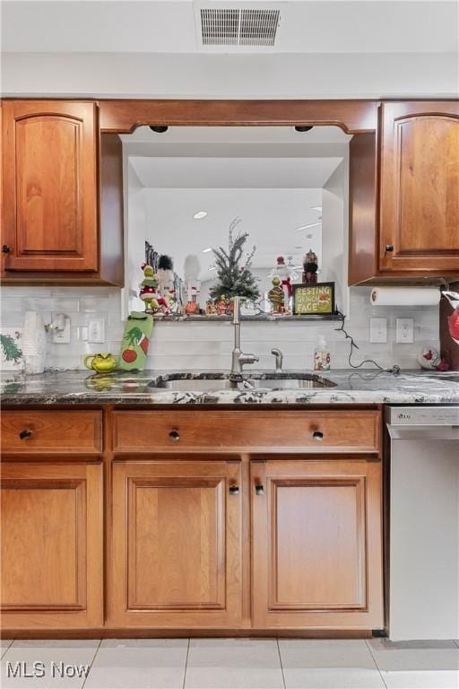 kitchen with backsplash, sink, dark stone countertops, dishwasher, and light tile patterned flooring