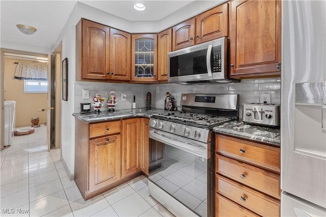 kitchen featuring backsplash, stainless steel appliances, and dark stone counters