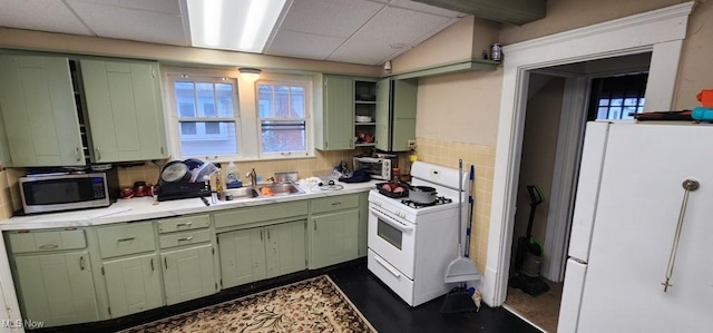 kitchen with white appliances, green cabinetry, and sink