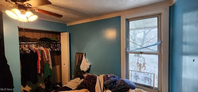 bedroom with ceiling fan, a textured ceiling, and a closet