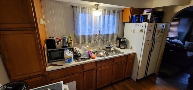 kitchen featuring dark hardwood / wood-style flooring, sink, hanging light fixtures, and white refrigerator