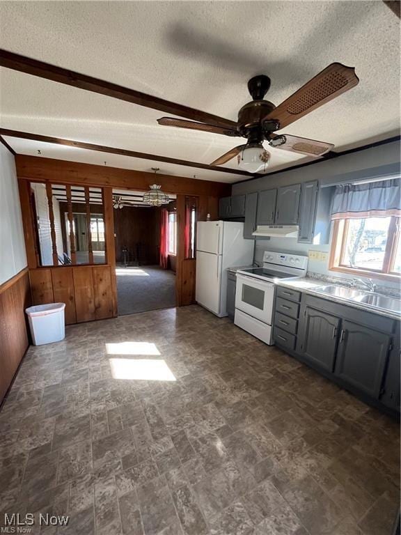 kitchen with sink, a textured ceiling, white appliances, gray cabinets, and wooden walls