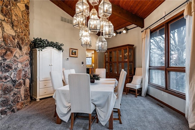 dining room with vaulted ceiling with beams, a fireplace, wooden ceiling, and dark colored carpet