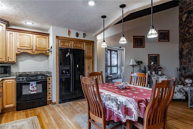 dining area with a textured ceiling, light hardwood / wood-style floors, and lofted ceiling