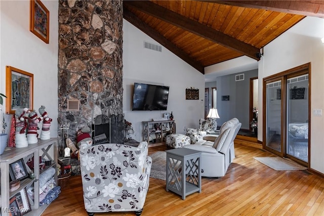 living room with high vaulted ceiling, a stone fireplace, light hardwood / wood-style flooring, beam ceiling, and wood ceiling