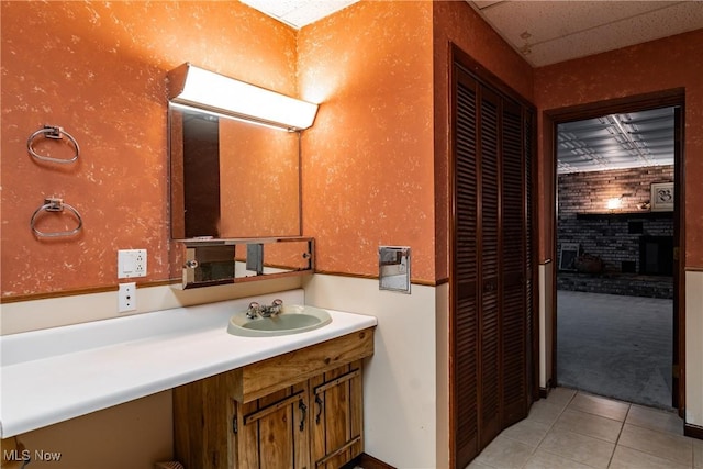 bathroom featuring tile patterned floors, vanity, and a brick fireplace