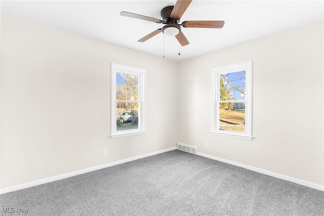 carpeted empty room featuring a wealth of natural light and ceiling fan