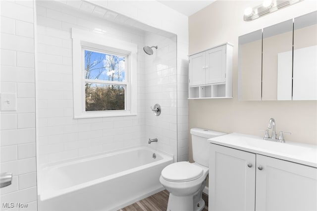 full bathroom featuring vanity, wood-type flooring, tiled shower / bath combo, and toilet