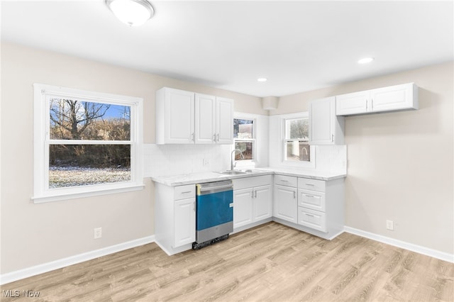 kitchen with light stone counters, stainless steel dishwasher, sink, light hardwood / wood-style flooring, and white cabinets