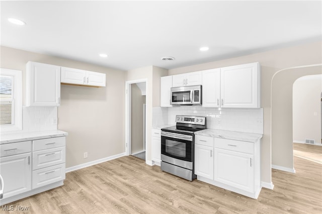 kitchen with stainless steel appliances, white cabinetry, tasteful backsplash, and light hardwood / wood-style floors