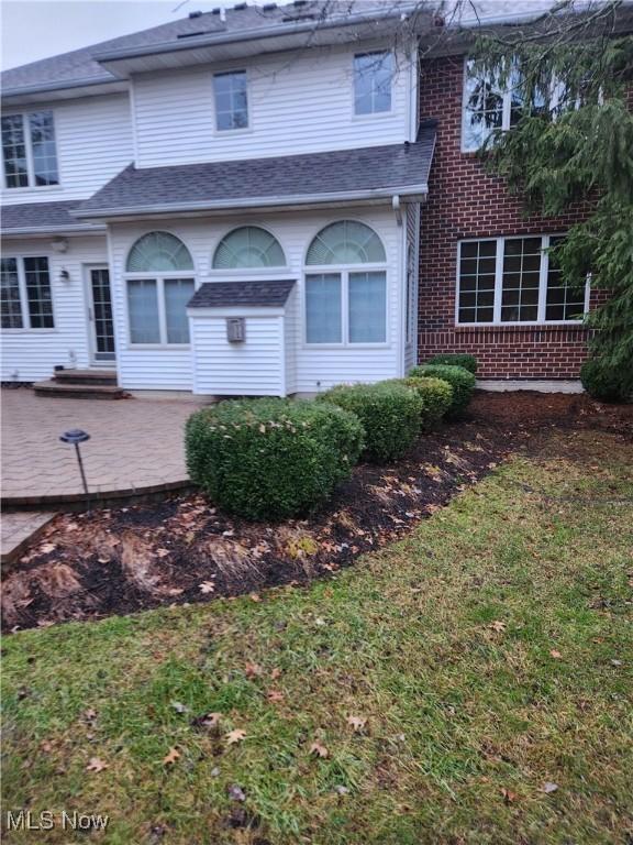 back of property with a lawn and a patio area