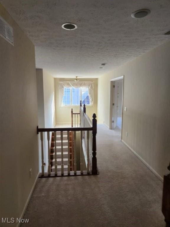 corridor featuring carpet flooring and a textured ceiling