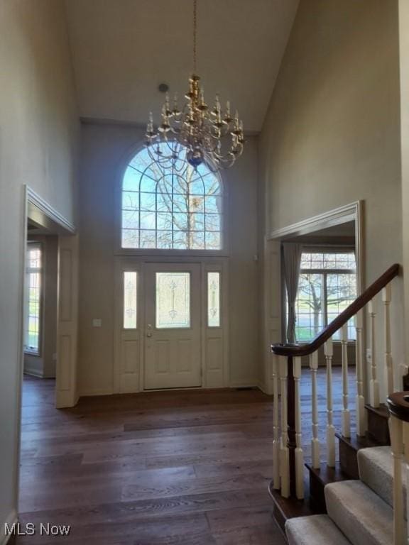 entryway featuring high vaulted ceiling, dark wood-type flooring, and a notable chandelier