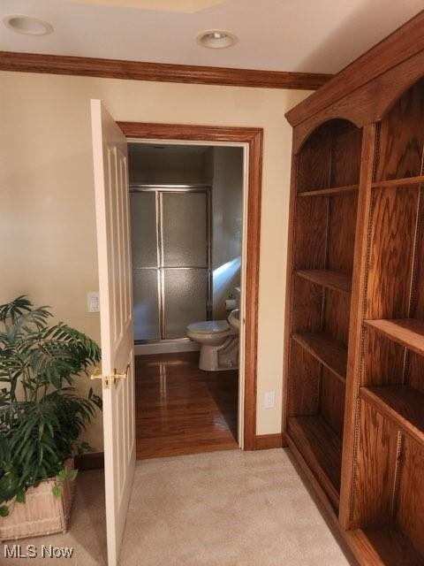 bathroom featuring wood-type flooring, toilet, a shower with door, and crown molding