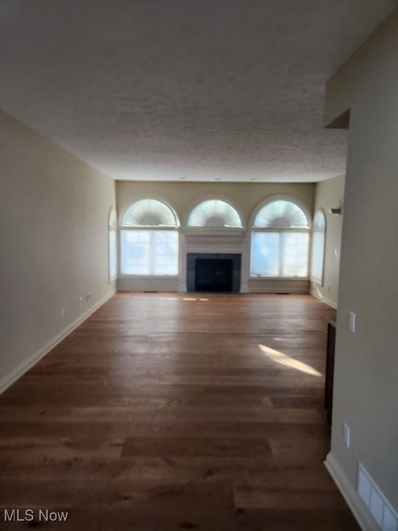 unfurnished living room with a textured ceiling and dark wood-type flooring