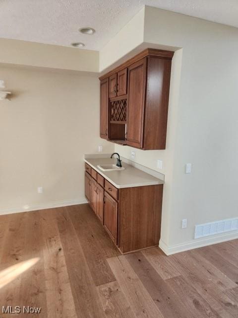 kitchen featuring sink, a textured ceiling, and light wood-type flooring