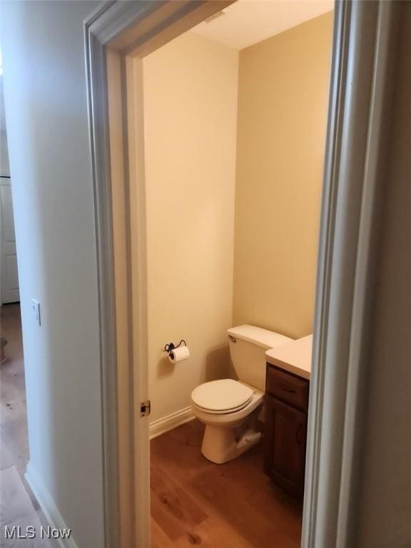 bathroom with vanity, wood-type flooring, and toilet