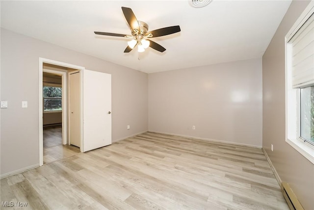 empty room featuring ceiling fan, light hardwood / wood-style floors, and a baseboard heating unit