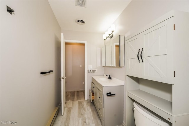 bathroom with wood-type flooring, vanity, and toilet