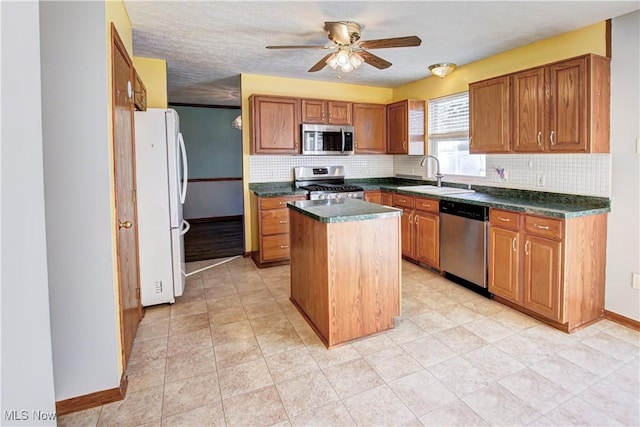 kitchen featuring tasteful backsplash, stainless steel appliances, ceiling fan, sink, and a kitchen island