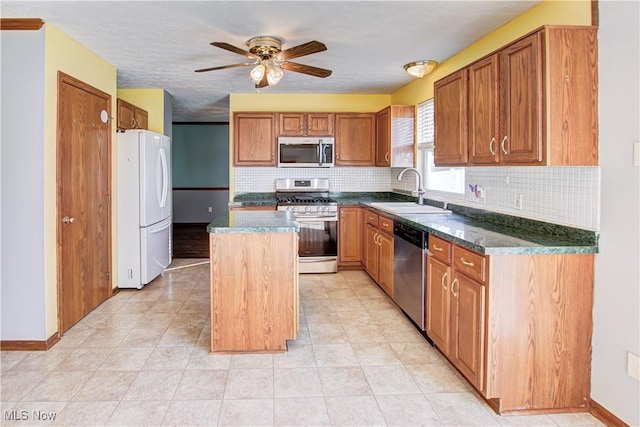 kitchen featuring ceiling fan, sink, stainless steel appliances, tasteful backsplash, and a kitchen island