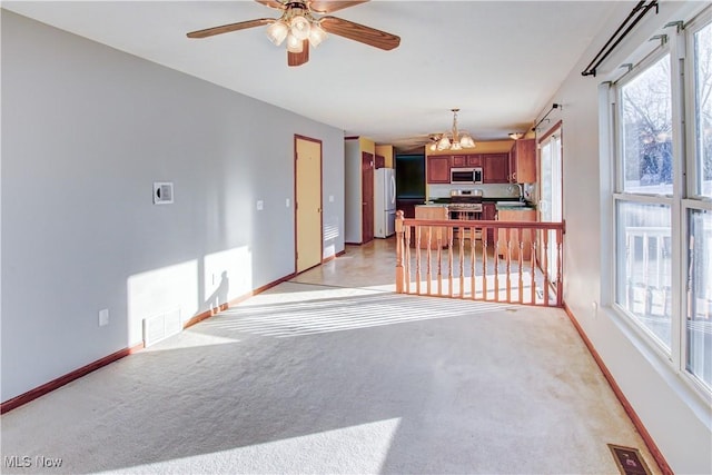 empty room with ceiling fan with notable chandelier, light colored carpet, and sink