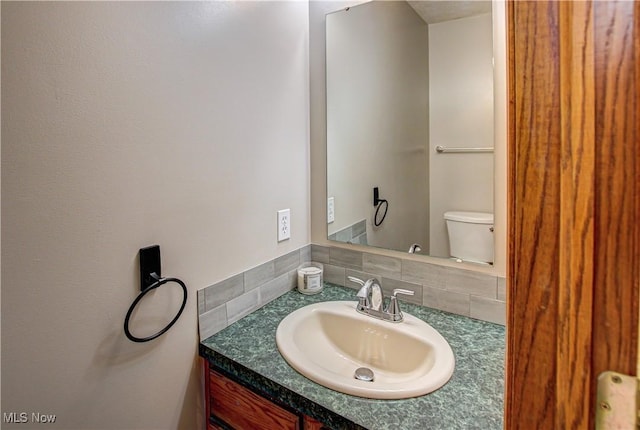 bathroom featuring vanity, tasteful backsplash, and toilet