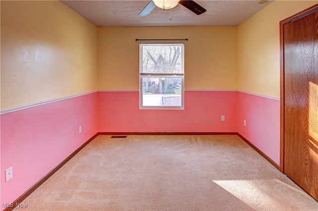 spare room with light carpet, a textured ceiling, and ceiling fan