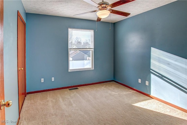 carpeted spare room featuring ceiling fan and a textured ceiling