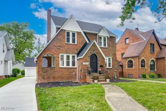 english style home featuring an outbuilding, a garage, and a front lawn