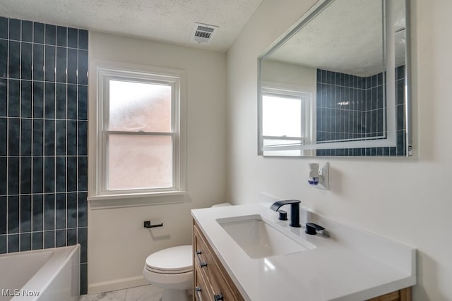 full bathroom with tiled shower / bath, vanity, a textured ceiling, and toilet