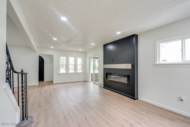 unfurnished living room with a textured ceiling, light hardwood / wood-style floors, and a fireplace