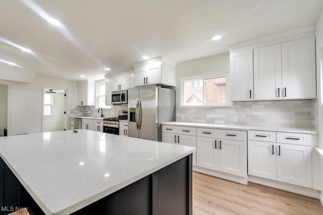 kitchen featuring white cabinetry, light hardwood / wood-style flooring, stainless steel appliances, and light stone counters